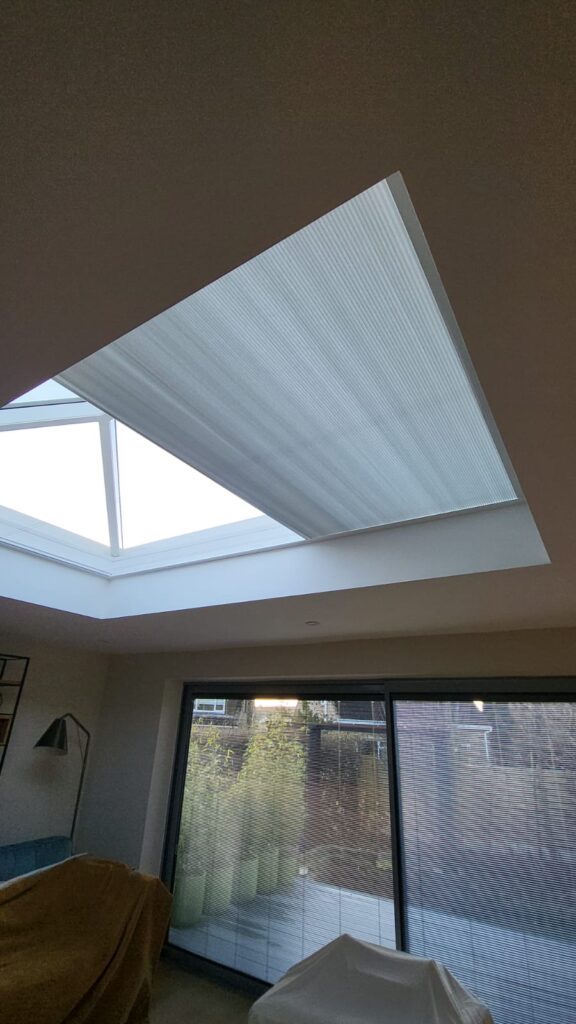 White roof lantern blinds half open beneath overhead glazing